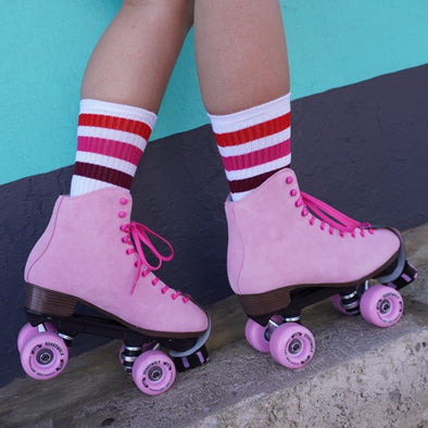 person wearing white mid calf socks with marron pink red stripes and baby pink rollerskates 