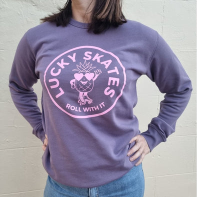 WOMENS WAERING PURPLE JUMPER WITH PINK LOGO OF PINEAPPLE WEARING ROLLER SKATES lucky skates roll with it 