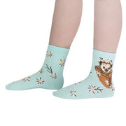 KID WEARING BLUE CREW SOCK WITH PATTERN OF HEDGEHOG IN FLOWER POT AND DAISIES