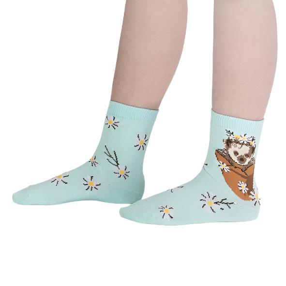 KID WEARING BLUE CREW SOCK WITH PATTERN OF HEDGEHOG IN FLOWER POT AND DAISIES