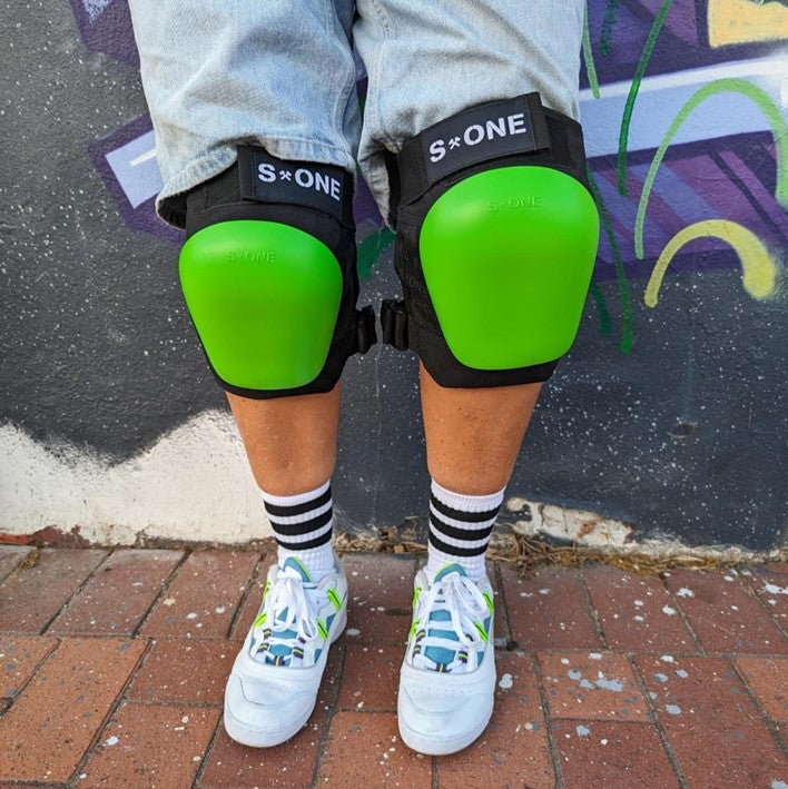 PERSON WEARING BLACK S ONE KNEE PADS WITH LIME GREEN RECAPS