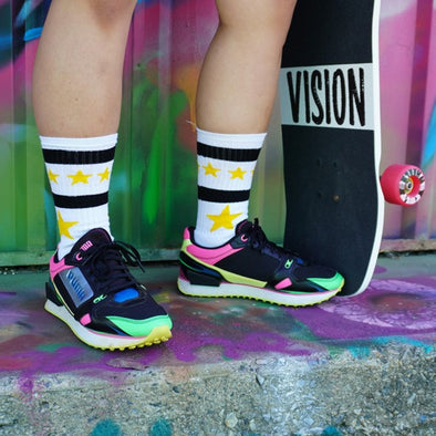persn wearing white mid calf socks with yellow stars white holding a skateboard 