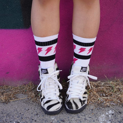 person wearing white mid calf socks with magenta lighting bolts and zebra shoes 