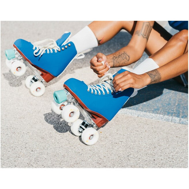 person wearing electric blue high top chaya rollerskates cream laces teal toe stop white outdoor wheels