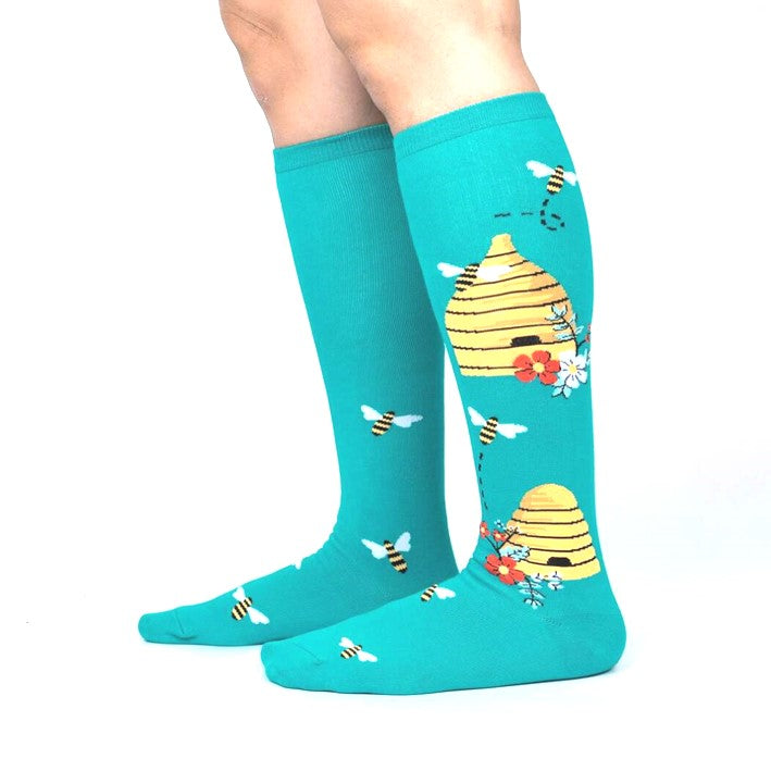 PERSON WEARING TEAL KNEE HIGH SOCKS WITH BEE HIVES ON SIDE AND BEES OVER SOCK