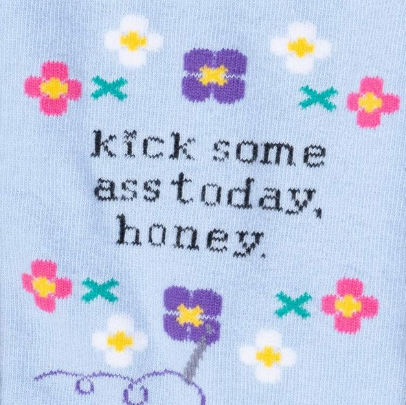 close up of text on light blue sock saying "kick some ass today, honey." with flowers around text