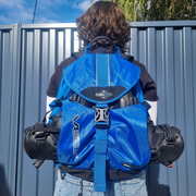 PERSON WEARING BLUE SKATE BACKPACK WITH INLINE SKATES IN FRONT COMPARTMENT