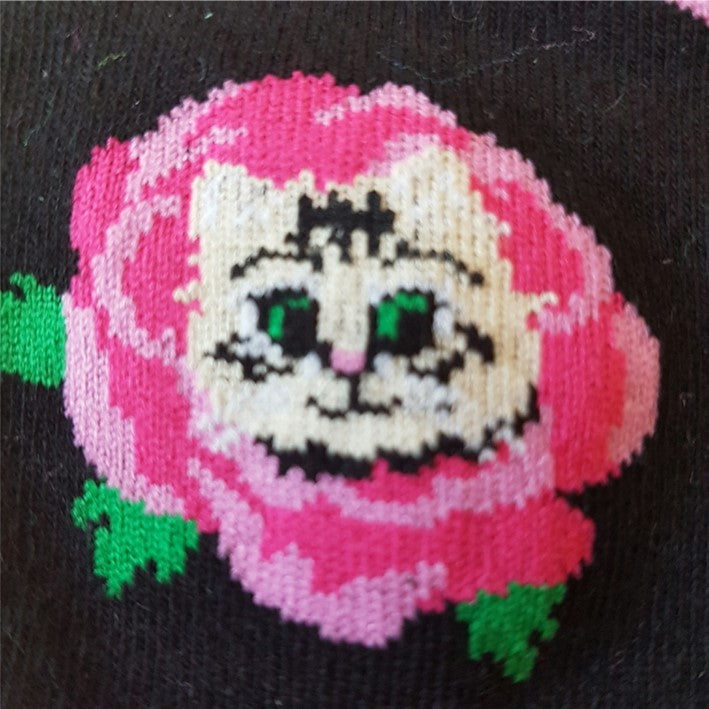 CLOSE UP OF BLACK FRILLED CREW SOCK WITH PINK ROSE BEHIND CAT HEAD