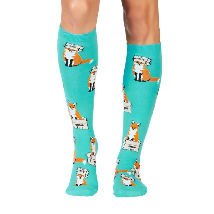 PERSON WEARING TEAL KNEE HIGH SOCKS WITH PRINT OF ORANGE FOXES  SITTING IN BOXES