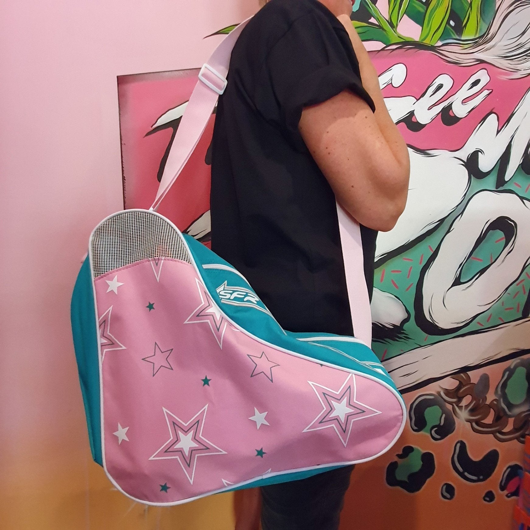 PERSON HOLDING PINK TEAL STAR PATTERN SFR SHOULDER CARRY SKATE BAG