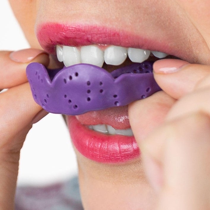 PERSON PUTTING IN PURPLE SISU MOUTHGUARD