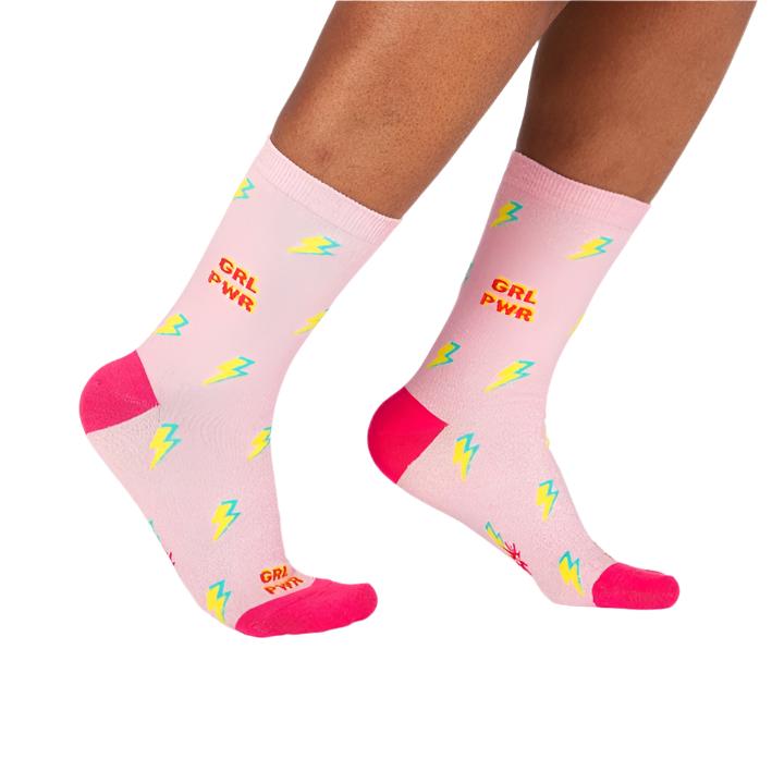 PERSON WEARING LIGHT PINK CREW SOCKS WITH LIGHTENING BOLTS AND TEXT "GRL PWR"