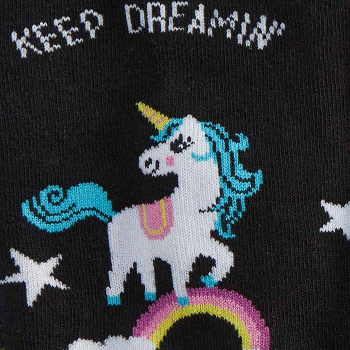 CLOSE UP OF BLACK SOCK WITH UNICORN ON RAINBOW WITH TEXT ABOVE "KEEP DREAMIN'"