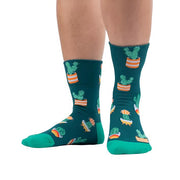 PERSON WEARING FORREST GREEN CUFFED CREW SOCKS WITH LIGHTER GREEN HEEL AND TOE WITH CACTUS IN RETRO POTS