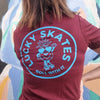 WOMENS WEARING MAROON TEE WITH BLUE LOGO OF PINEAPPLE WEARING ROLLER SKATES lucky skates roll with it 