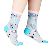 PERSON WEARING GREY CREW SOCKS WITH PATTERN OF PURPLE BLUE AND PINK RETRO CASSETTE TAPES