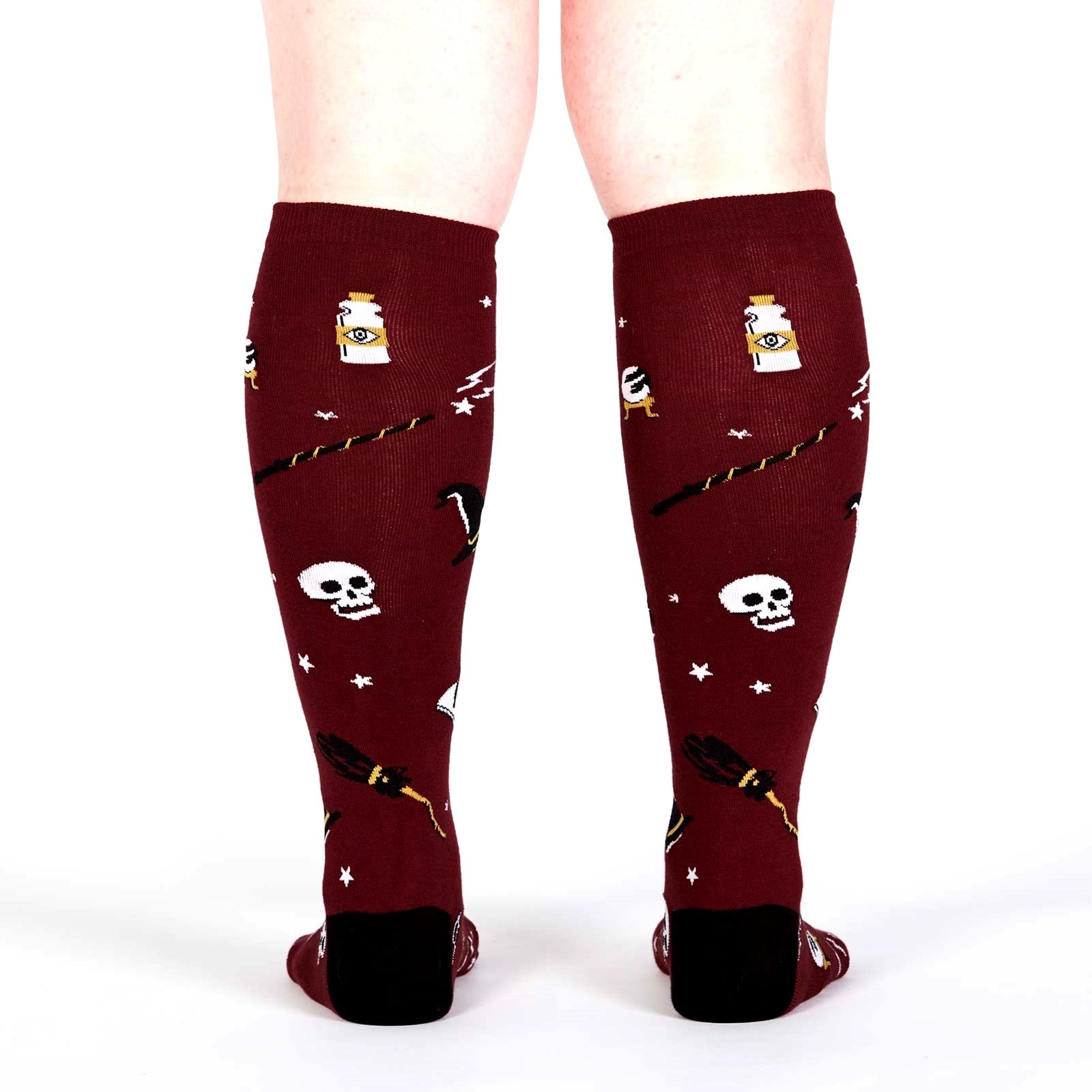 REAR VIEW OF PERSON WEARING MAROON SOCKS WITH POTIONS, WANDS, SKULLS AND STARS